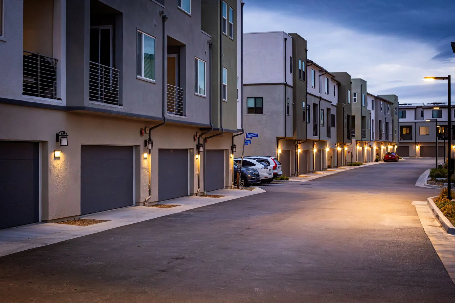 Newer low-rise multifamily housing with attached garages at dusk